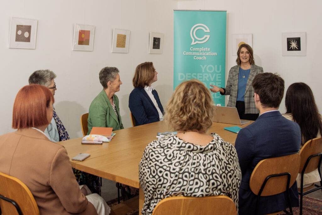 Kerry leading a workshop with attendees sitting around a table